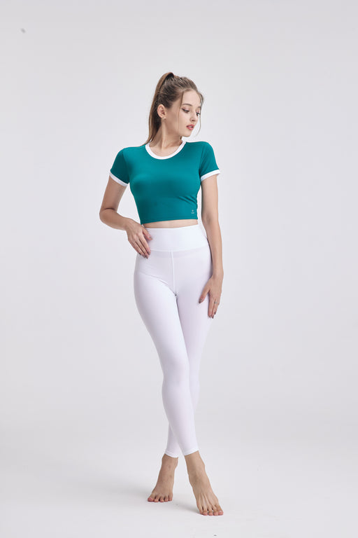 Woman wearing ElevateFit™ Criss Cross Crop Top with Bra Support in teal and white leggings against plain background
