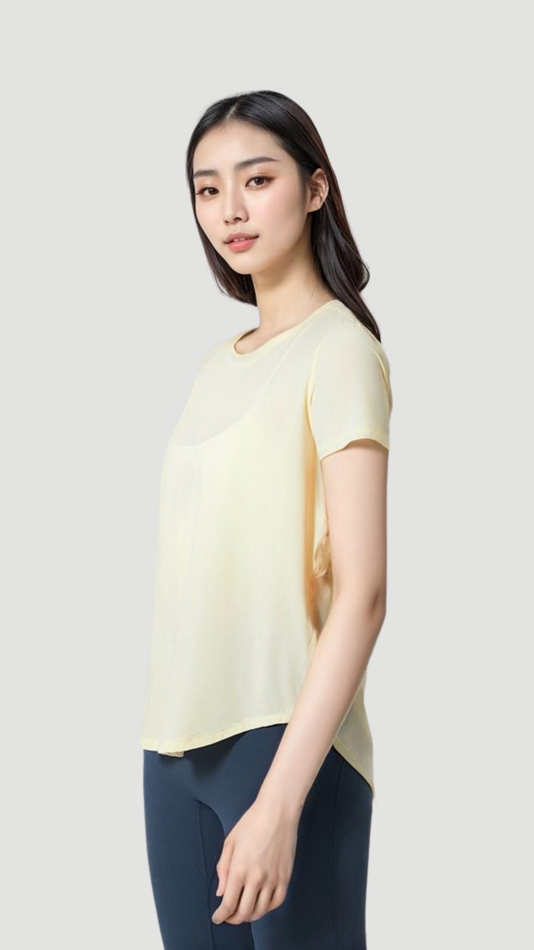 Woman wearing a light yellow Aero Flow Active Tee with round neck and back slit, paired with navy leggings.
