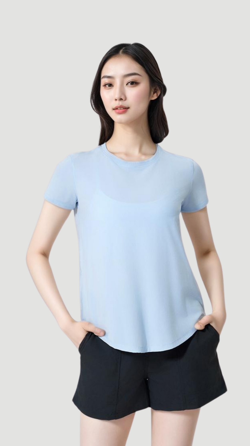 Woman wearing a light blue Aero Flow Active Tee with a round neck and black shorts against a gray background.