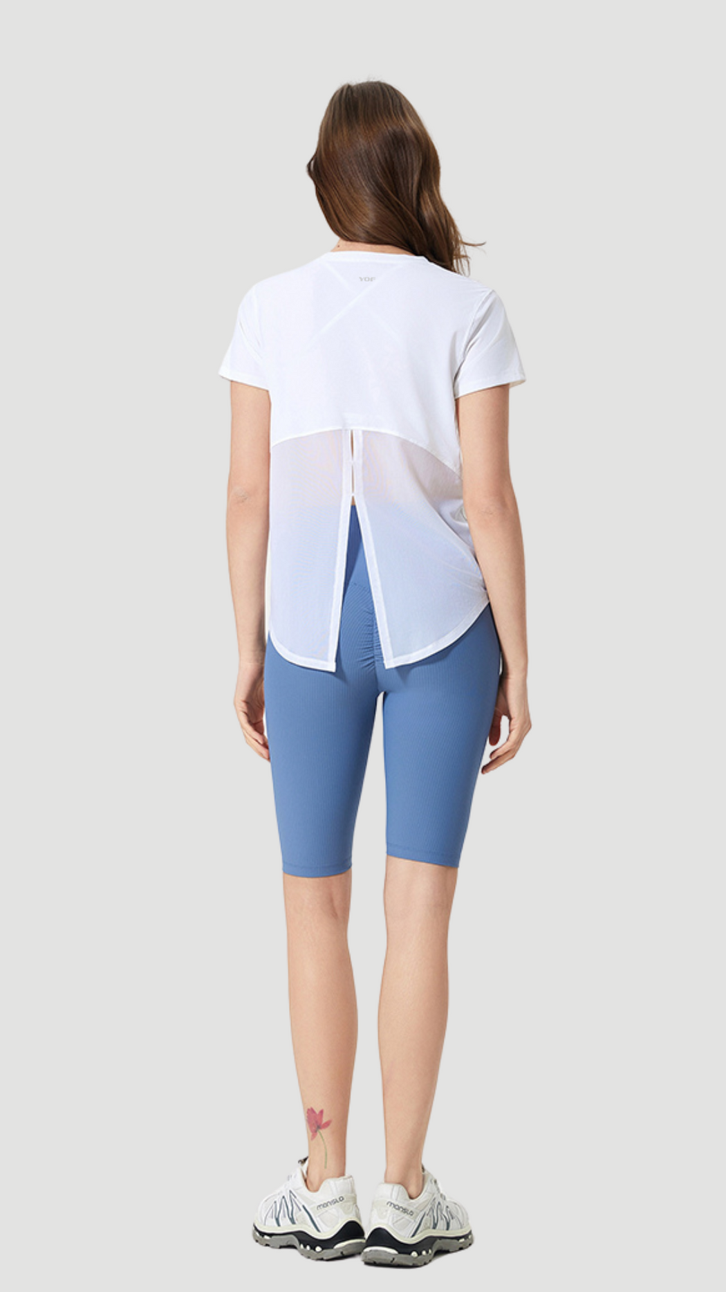 Aero Flow Active Tee shown from back with white fabric, back slit design, and paired with blue shorts.