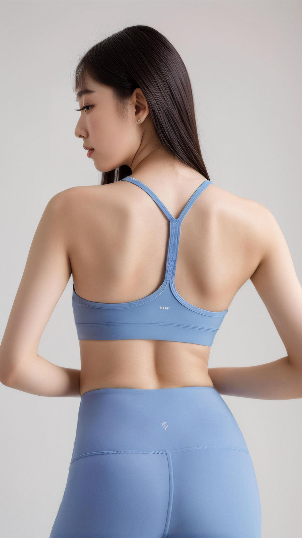 Woman wearing light blue AeroFlex Strappy Bra with Y-back design and matching leggings, shown from the back.