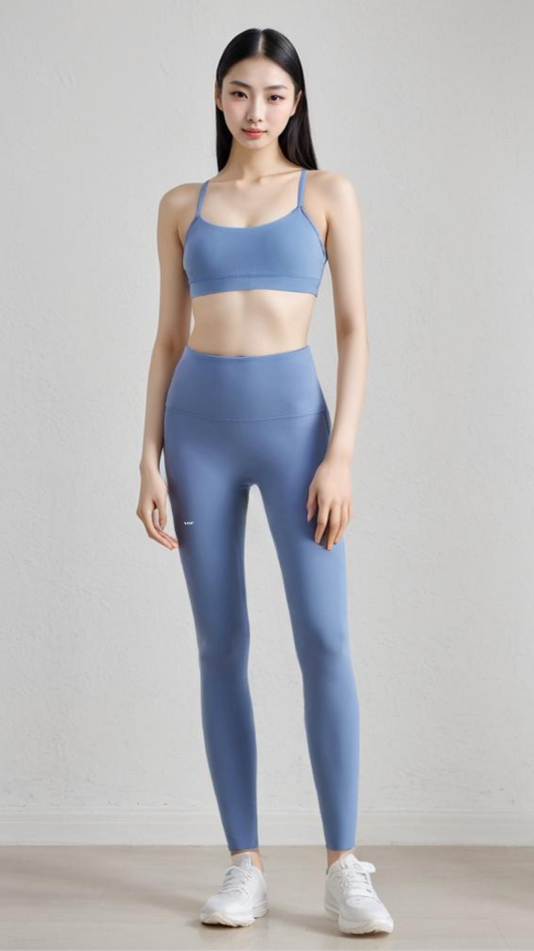 Woman wearing blue AeroFlex Strappy Bra with matching leggings, standing against a plain light background.