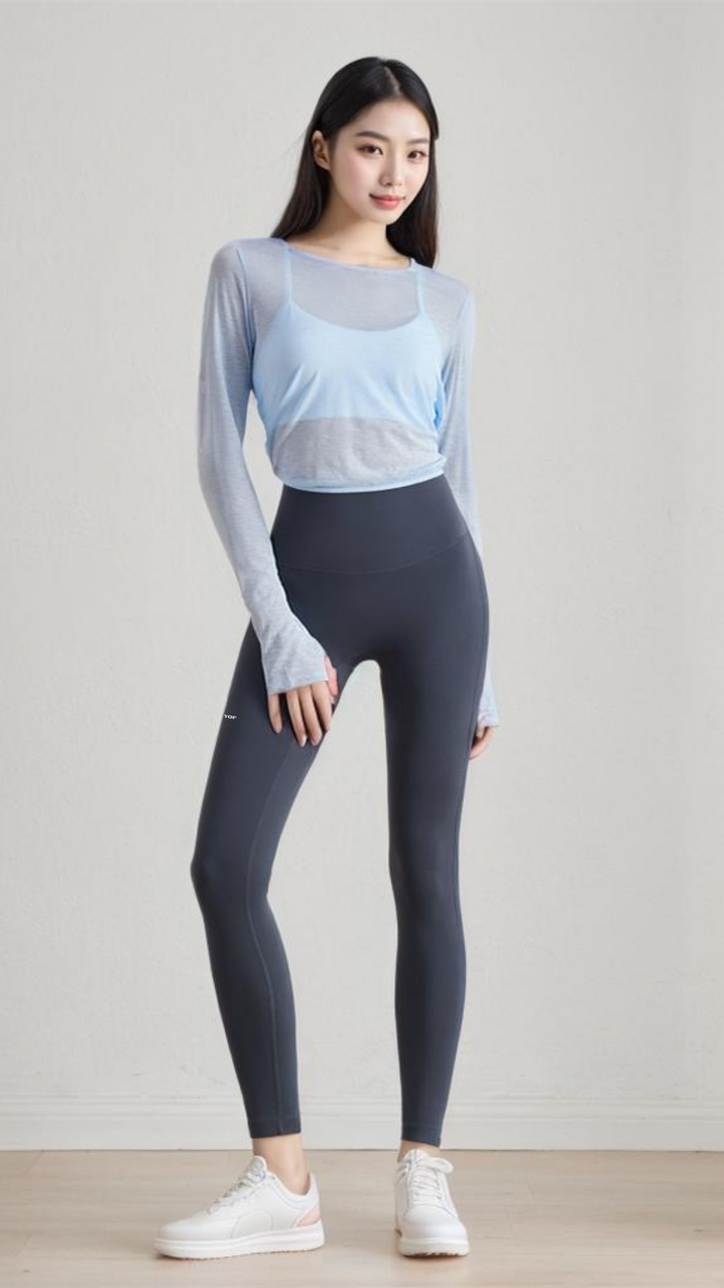 Woman wearing AeroFlex Strappy Bra with long sleeve top and high-waisted leggings, standing against white wall.